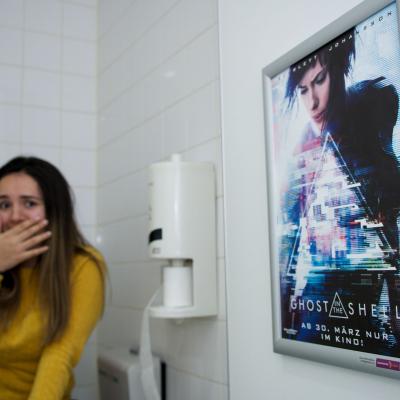 Filmwerbung als Poster mit Alurahmen auf heller Rückwand in edler Restaurant Toilette