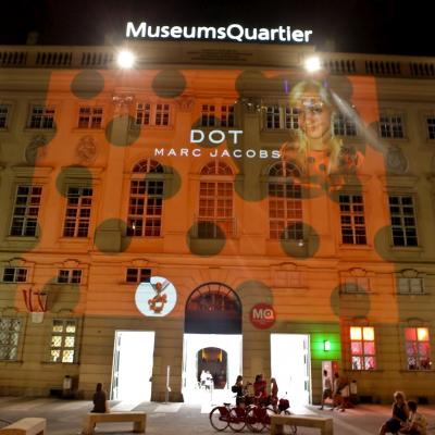 Projektion mit Werbung für Parfum Dots auf Fassade MQ in der Nacht