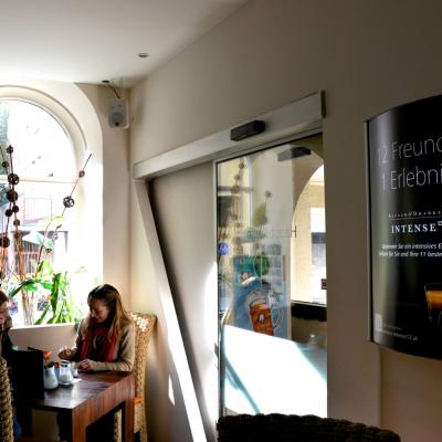 Weisse Schrift auf Schwarzem Werbeplakat, beleuchtet an der Wand, für Teekapseln von Nespresso in modernem Bar Restaurant mit großem Fenster im Hintergrund