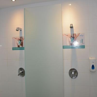 Klebefolien in weiß gekachelter Dusche in Fitness Studio mit Werbung für Depilan