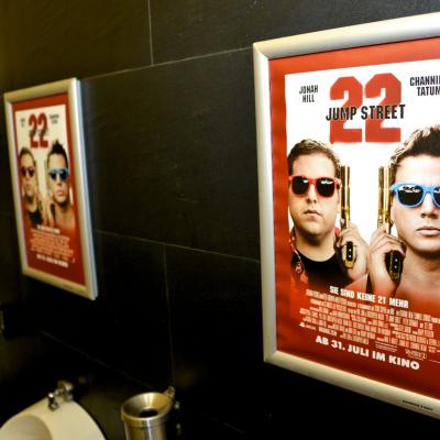 Filmwerbung in Alurahmen auf schwarzen Kacheln in Männertoilette Restaurant 