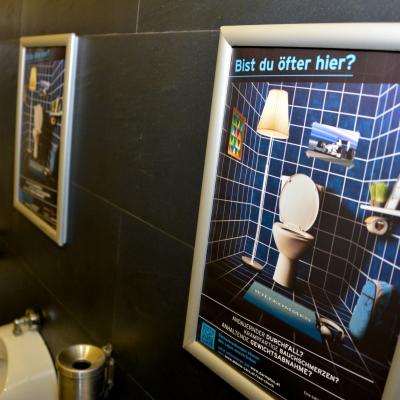 Werbeposter mit Alurahmen auf Restaurant Toilette auf dunkler Wand