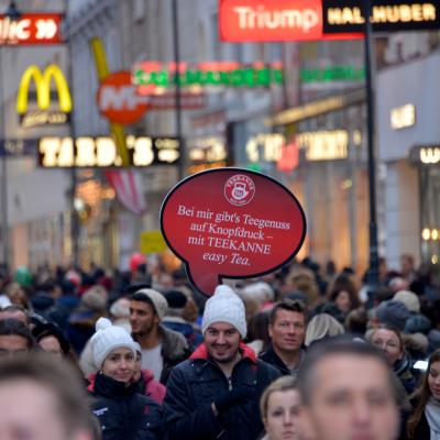 eine rote Sprechblase aus Kunststoff über dem Kopf eines Promotors in der Innenstatt, beleuchtet, bei Nacht