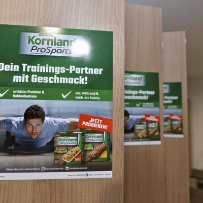 Grünes Werbeposter für Kornland an der Innenseite von Umkleidekabinen im Fitness Studio
