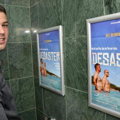 Poster mit Filmwerbung auf Restauranttoilette mit Alurahmen an dunkler Wand