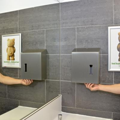 Filmwerbung in Restaurant Toilette mit Alurahmen auf grauer Wand