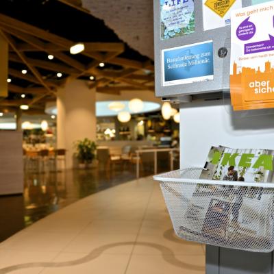 IKEA Katalog liegt in durchsichtigem Korb an Postkartenständer in modernem Bar Restaurant