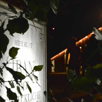 Eine große Felstafel / Grabstein als graue Werbetafel in der Innenstadt bei Nacht angeleuchtet
