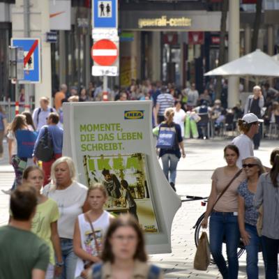 Citylight an Fahrrad mit Promotoren in Fußgängerzone mit viele Passanten