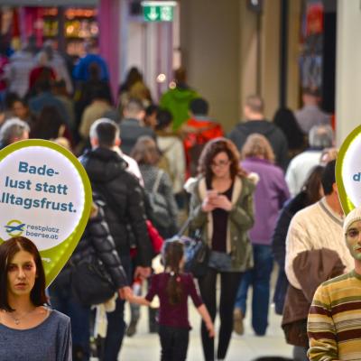 Promotor mit Sprechblase und Werbung über dem Kopf in Passantenmenge