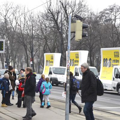 16 Bogen Plakat auf weissem Auto mit gelber Werbung für Radio 88,6 im Großstadtverkehr