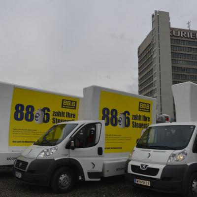 16 Bogen Plakat auf weissem Auto mit gelber Werbung für Radio 88,6 im Großstadtverkehr