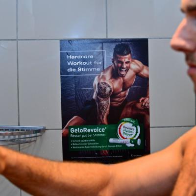 Werbeposter in Dusche von Fitness Studio auf weissen Kacheln
