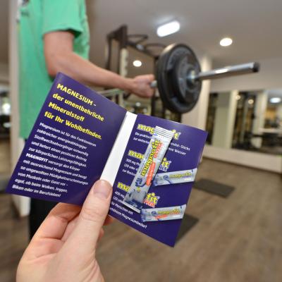 Produktproben mit Folder in schickem Fitness Studio im Trainingsbereich