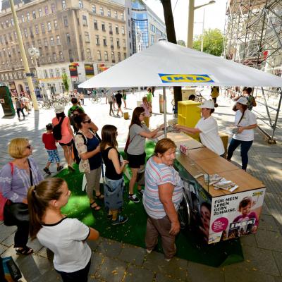 Passanten vor Promotions Dreirad mit Werbung für Ikea in Fußgängerzone