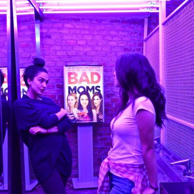 beleuchtetes Plakat im Vordergrund 2 hübsche Frauen in Szene Bar