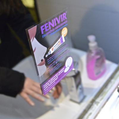 Frau blickt in Spiegel in Restaurant Toilette mit Werbeaufkleber für Fenivir