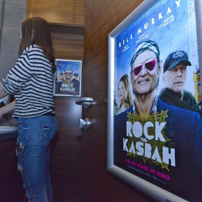 Filmwerbung als Poster mit Alurahmen auf dunkler Rückwand in edler Restaurant Toilette