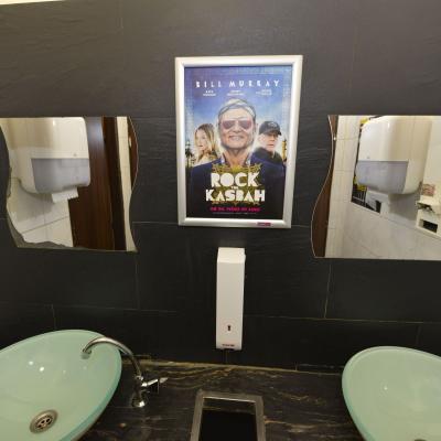 Filmwerbung als Poster mit Alurahmen auf dunkler Rückwand in edler Restaurant Toilette
