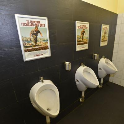 Filmwerbung als Poster mit Alurahmen auf dunkler Rückwand in edler Restaurant Toilette