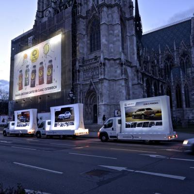 beleuchtetes 16 Bogen Plakat auf weissem Auto mit Werbung für Seat nachts im Großstadtverkehr