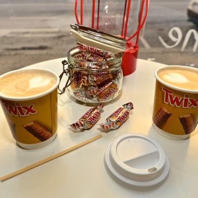 Kaffeebecher zum Mitnehmen mit Werbung für Twix in schicker Innenstadt Location