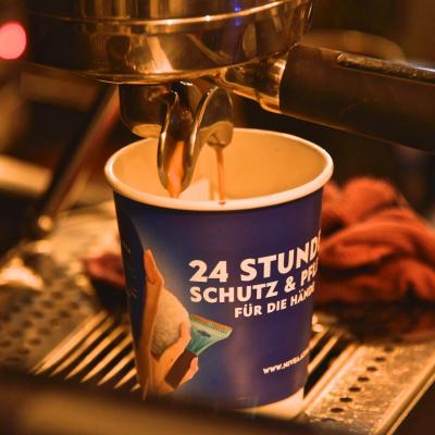 Kaffeebecher für unterwegs mit Nivea Werbung an Kaffeemaschine