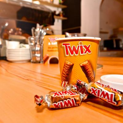 Kaffeebecher zum Mitnehmen mit Werbung für Twix in schicker Innenstadt Location