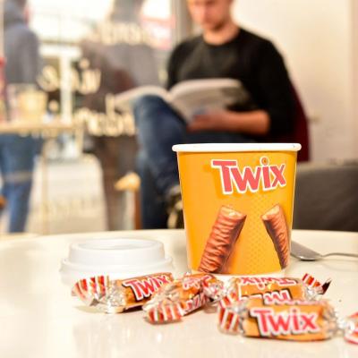 Kaffeebecher zum Mitnehmen mit Werbung für Twix in schicker Innenstadt Location