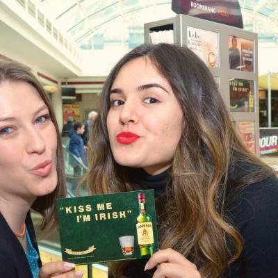 junge Frauen halten grüne Werbepostkarte mit Werbung für Jameson in die Kamera