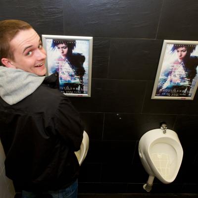Filmwerbung als Poster mit Alurahmen auf dunkler Rückwand in edler Restaurant Toilette