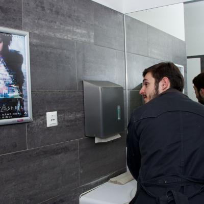 Filmwerbung als Poster mit Alurahmen auf dunkler Rückwand in edler Restaurant Toilette