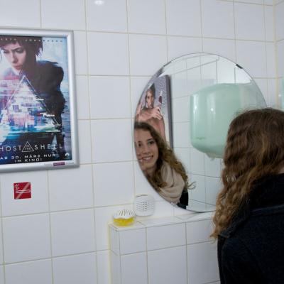 Filmwerbung als Poster mit Alurahmen auf heller Rückwand in edler Restaurant Toilette