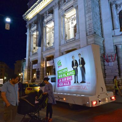 beleuchtetes 16 Bogen Plakat auf weissem Auto mit Werbung für die Grünen nachts im Großstadtverkehr