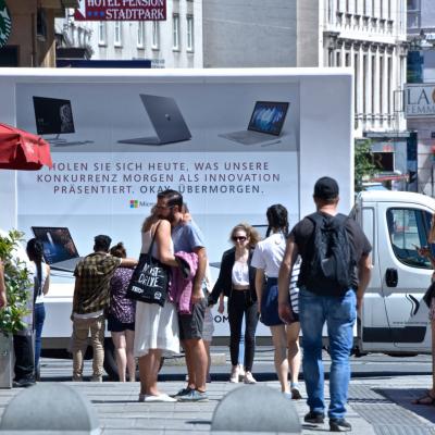 16 Bogen Plakat auf weissem Auto mit Werbung für Microsoft im Großstadtverkehr nachts