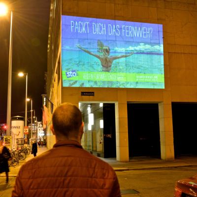 Projektion mit Werbung für STA Travel auf Fassade in der Nacht