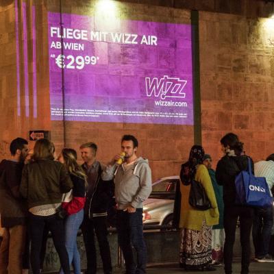 Projektion mit Werbung für Wizz Air auf Fassade in Großstadt in der Nacht