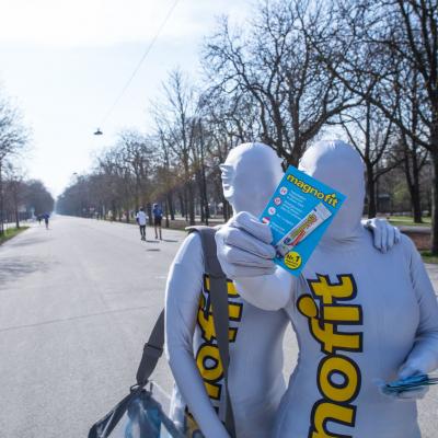 Sportler im Prater erhalten von Promotoren in silbernen Overalls Produktproben von Magnofit