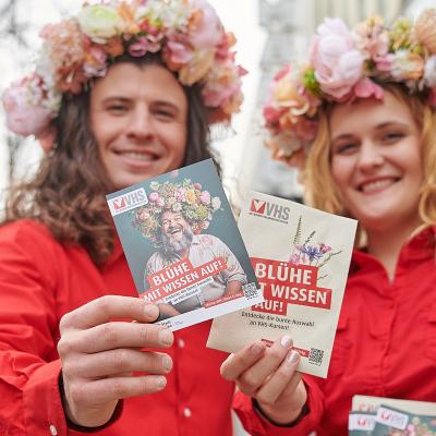 2 VHS Promoter:innen mit Blumenkränzen auf dem Haar